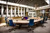 De raadszaal van de gemeente Lingewaard. Een ronde tafel met allemaal bureaustoelen eromheen.